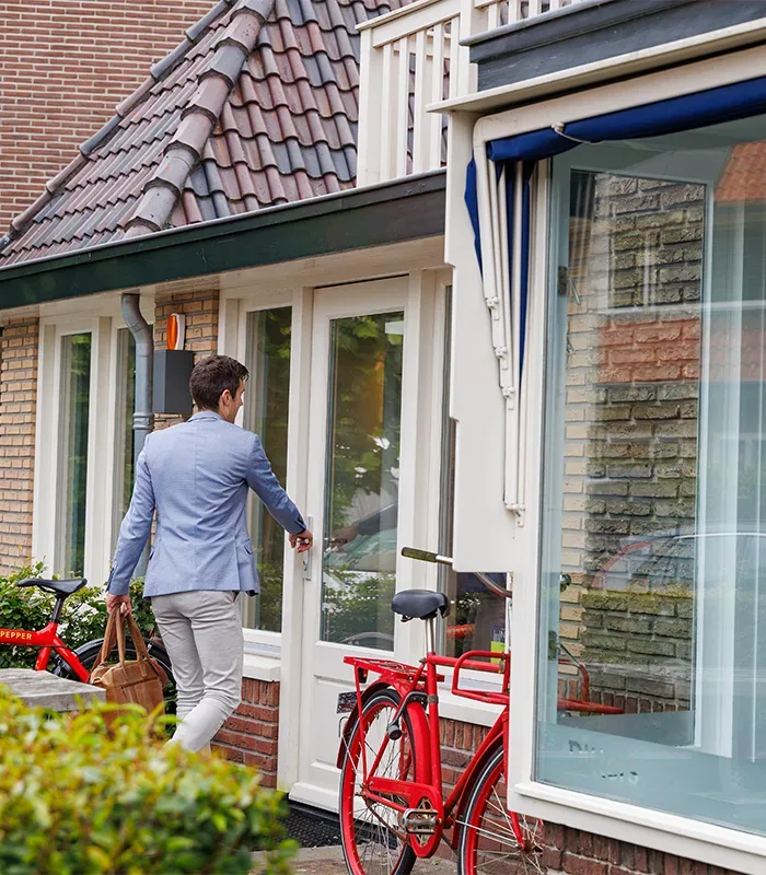 Makelaar Amersfoort – woningbezichtiging met Ditters Makelaars Jorik Otten, Makelaar van Ditters Amersfoort loopt naar de voordeur van de Ditters locatie in Amersfoort voor een bezichtiging, met aktetas en rode fiets bij de gevel.